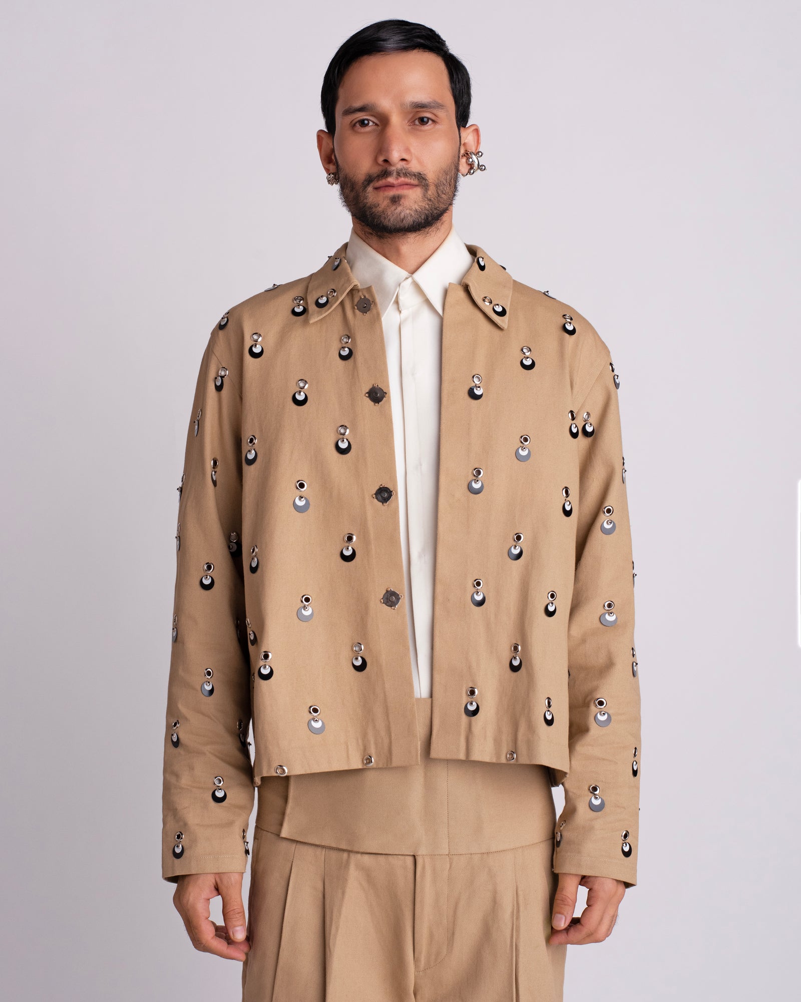 ROSANI The Carter jacket in khaki. Relaxed fit jacket with metallic eyelets, magnetic button accents and overlapping sequin detail. ANIMA and ANIMUS collection, front view.