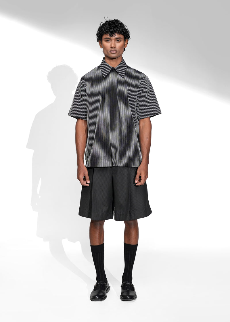 ROSANI The Frame Shirt in black, short-sleeve button-up with subtle pinstripes, styled with black tailored shorts, front view