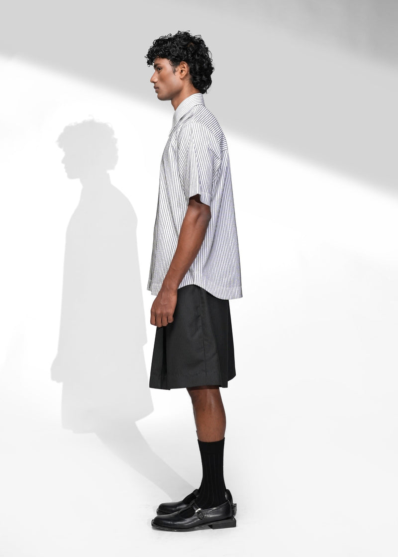 ROSANI The Frame Shirt in white, short-sleeve button-up with subtle pinstripes, styled with black tailored shorts, side view