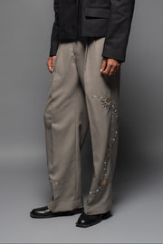 ROSANI The Kichka trouser in stone grey - wide-leg tailored trousers with floral thorn-inspired embellishment along the leg and elastic back waistband, front view, styled with a black blazer