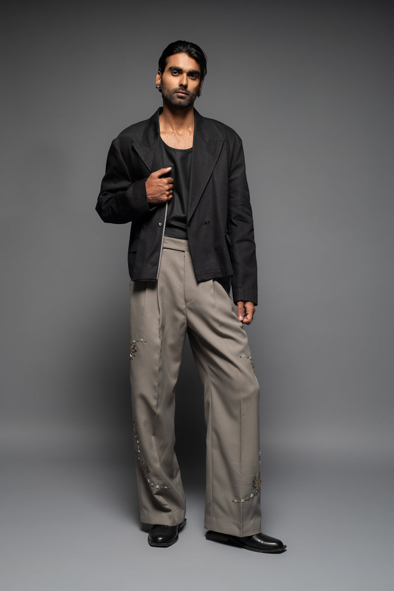 ROSANI The Kichka trouser in stone grey - wide-leg tailored trousers with floral thorn-inspired embellishment along the leg and elastic back waistband, full front view, styled with a black blazer