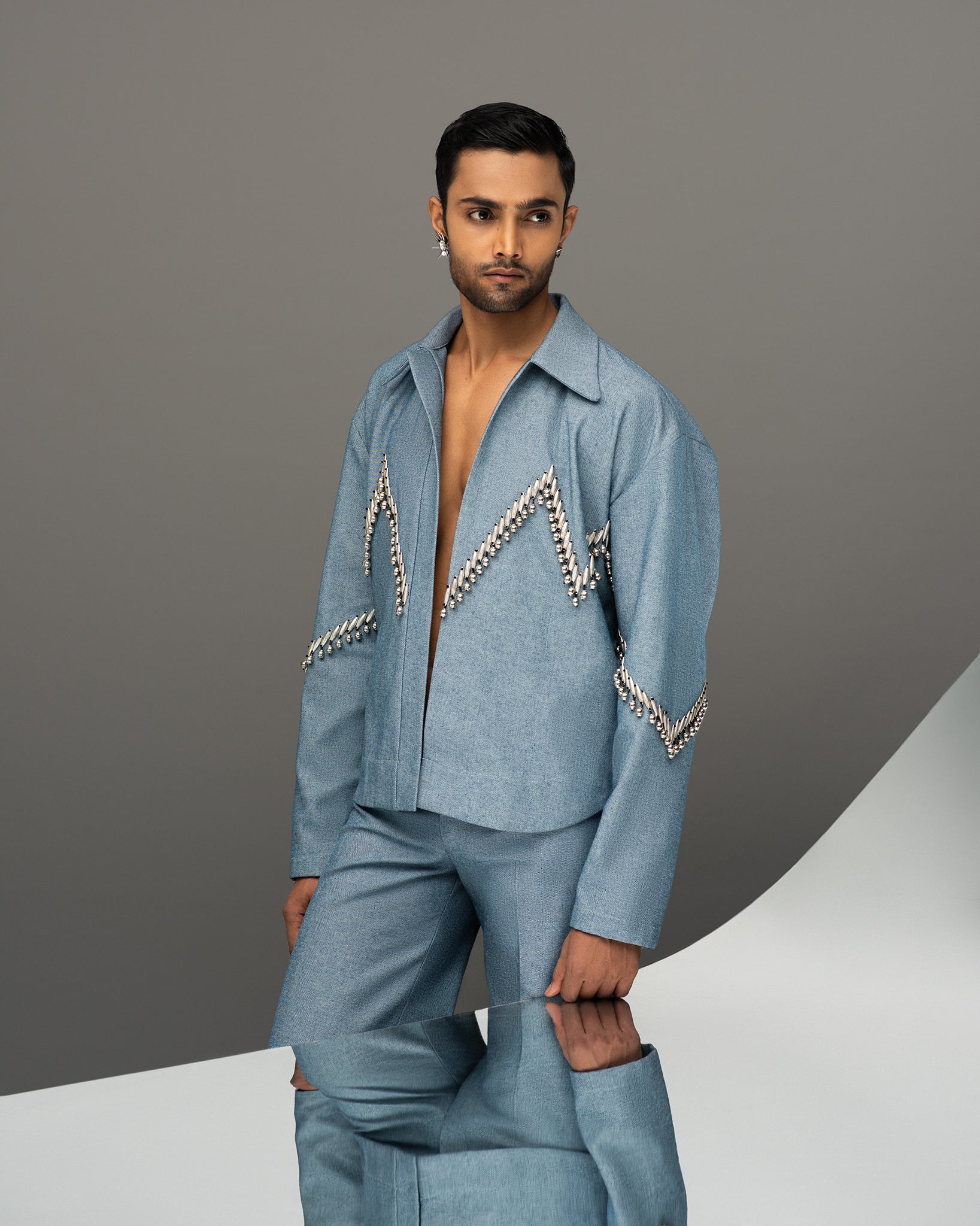 ROSANI Guarded Beauty collection image - model wearing The Munzwa jacket in light blue denim with silver embellished zigzag detailing, paired with matching trousers, editorial front view