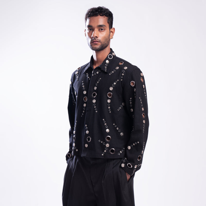 ROSANI The Arnos jacket in black, front view. Metallic eyelet embellishment and relaxed fit. DYMENSION collection.