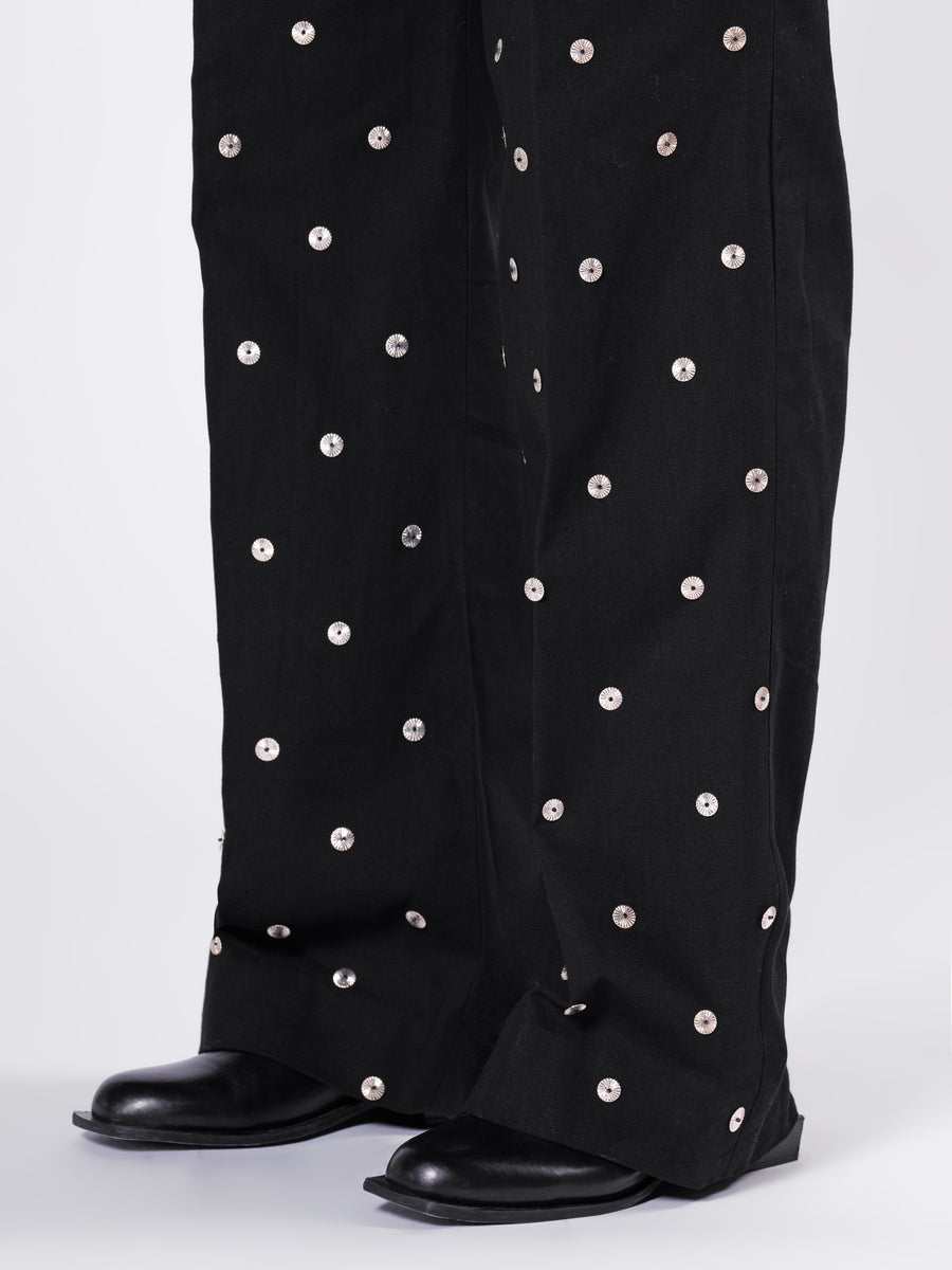 ROSANI The Blythe trouser in black. Close-up of scattered metallic disc detail on front panel.