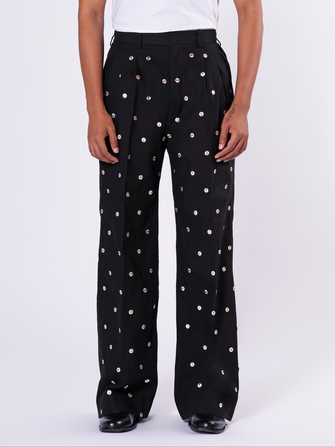 ROSANI The Blythe trouser in black. Wide-leg pleated trouser with metallic disc embellishment and back elastic waistband. ANIMA and ANIMUS collection, front view.