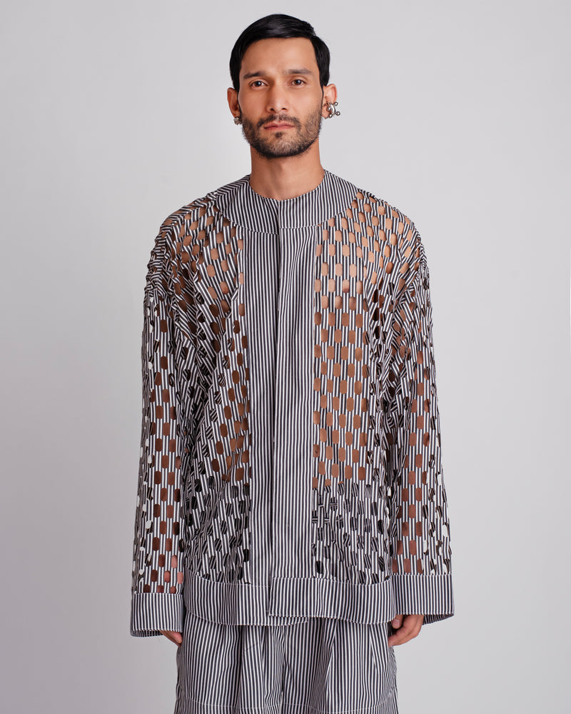 ROSANI The Emerson shirt in black and white stripes. Oversized laser-cut workwear shirt with metallic press buttons and geometric cut-out pattern. ANIMA and ANIMUS collection, front view.