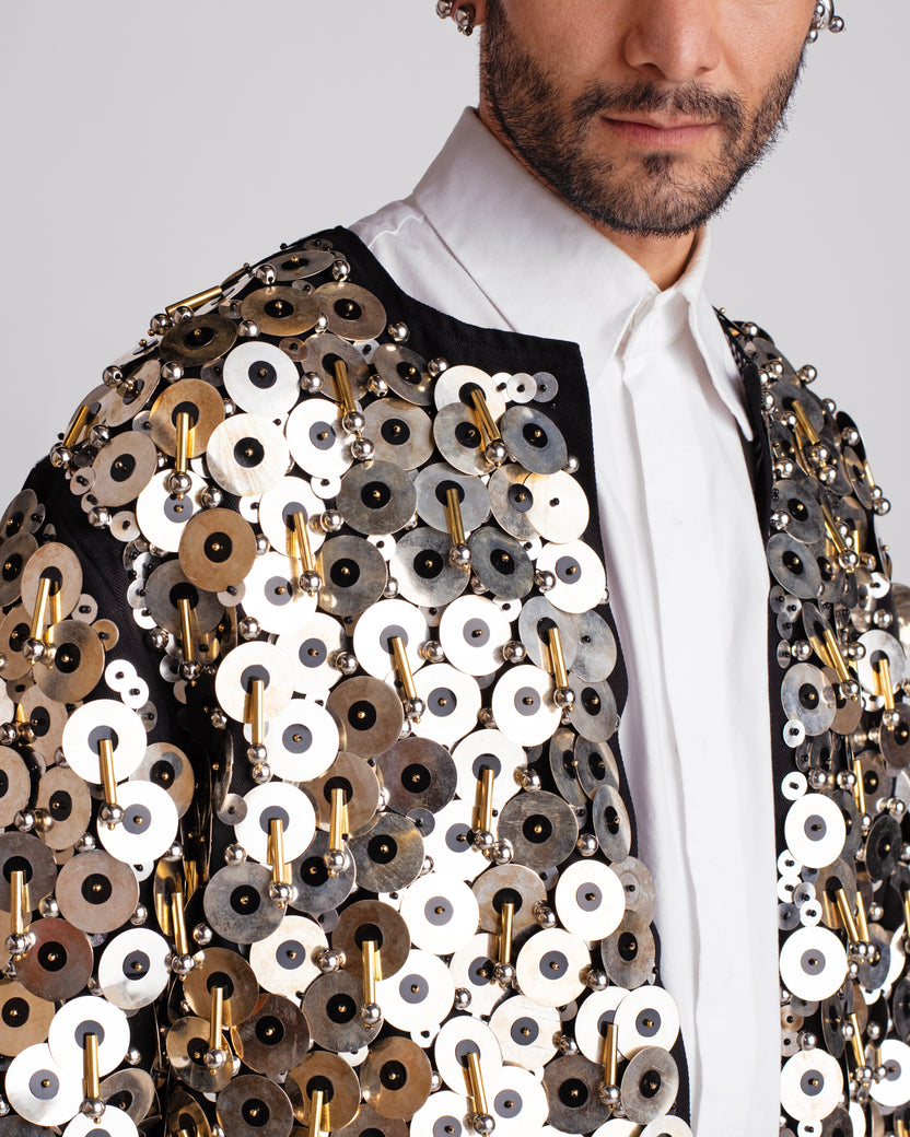 ROSANI The Jase jacket in black and silver. Close-up of metallic disc, bead and cylindrical pipe embroidery detail.