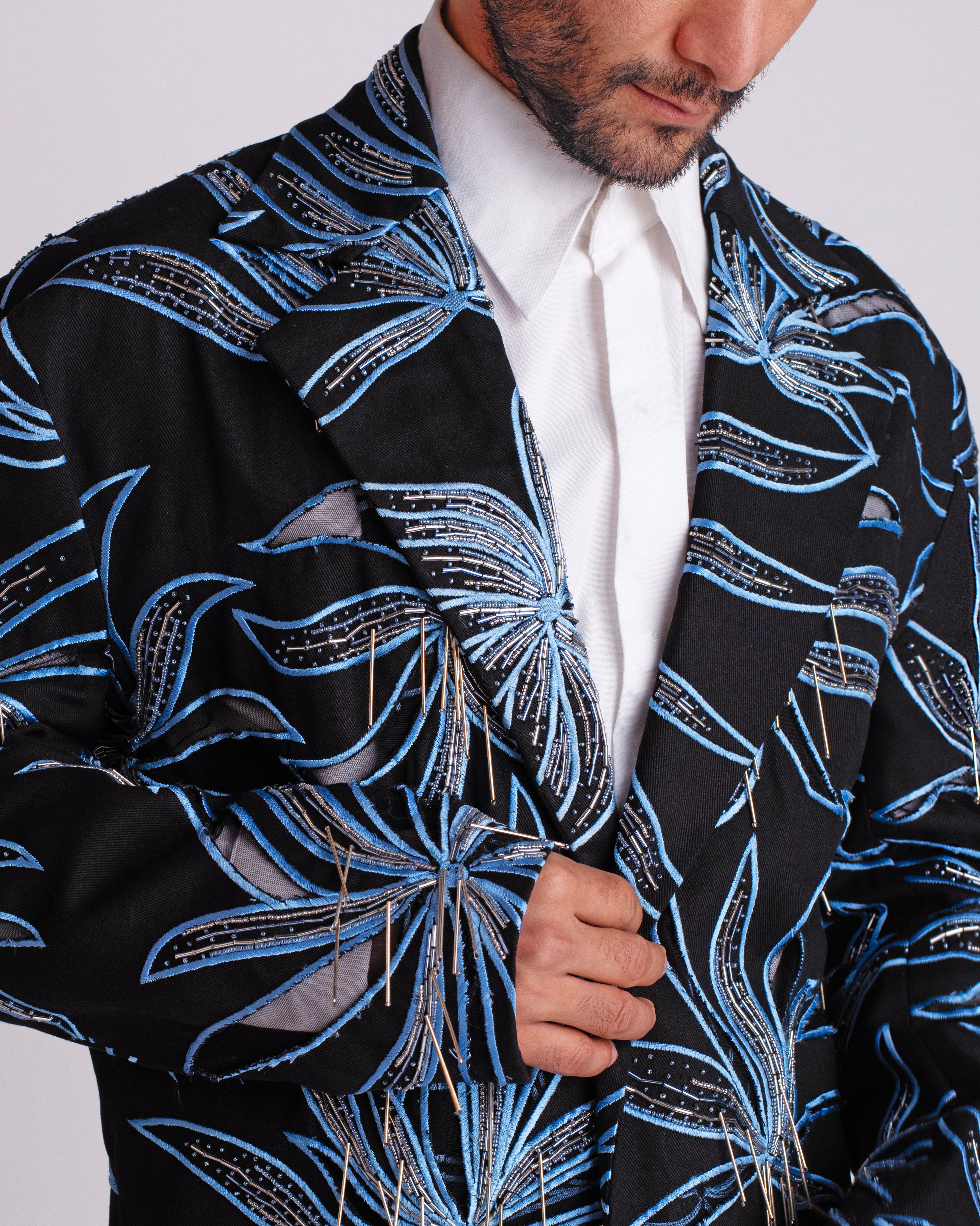 ROSANI The Noah coat in black. Close-up of hand cutwork, thread embroidery and hanging glass rod detail.