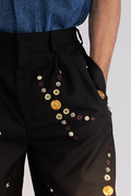 ROSANI The Orto trouser, side front angle. Pleat construction and metallic embellishment detail.
