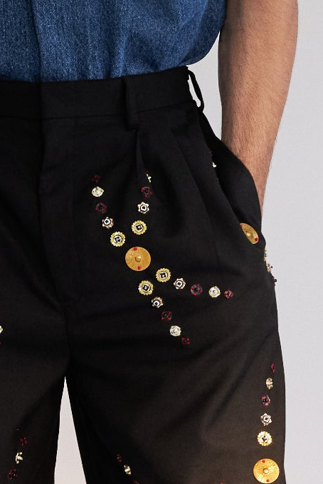 ROSANI The Orto trouser, side front angle. Pleat construction and metallic embellishment detail.